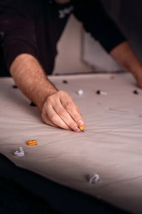 Hand placing pins along white fabric on the cutting table