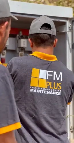 FM Plus maintenance technician in a charcoal tee with yellow trim, seen from behind