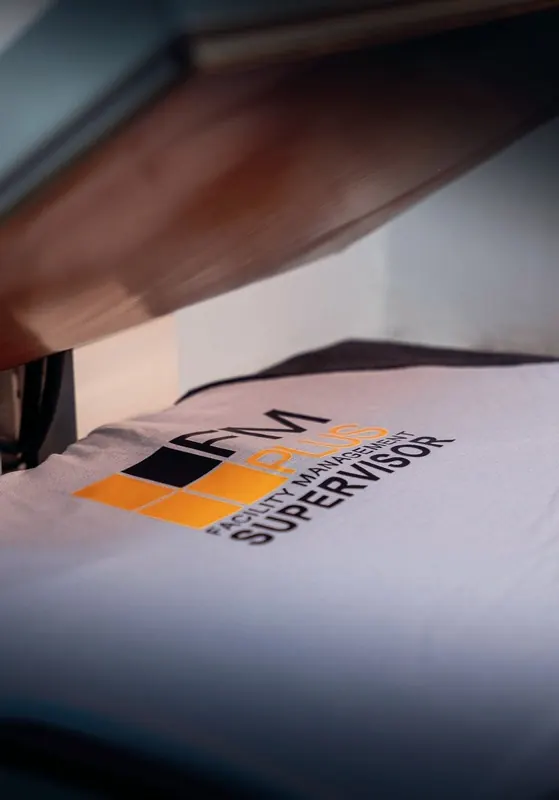 FM Plus supervisor logo being heat-pressed onto a white tee