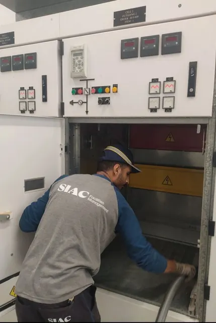SIAC technician in a grey and navy top working on electrical switchgear